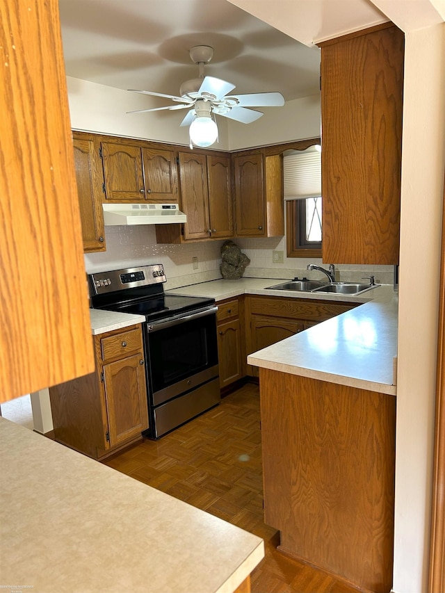 kitchen featuring under cabinet range hood, stainless steel range with electric cooktop, a sink, and light countertops