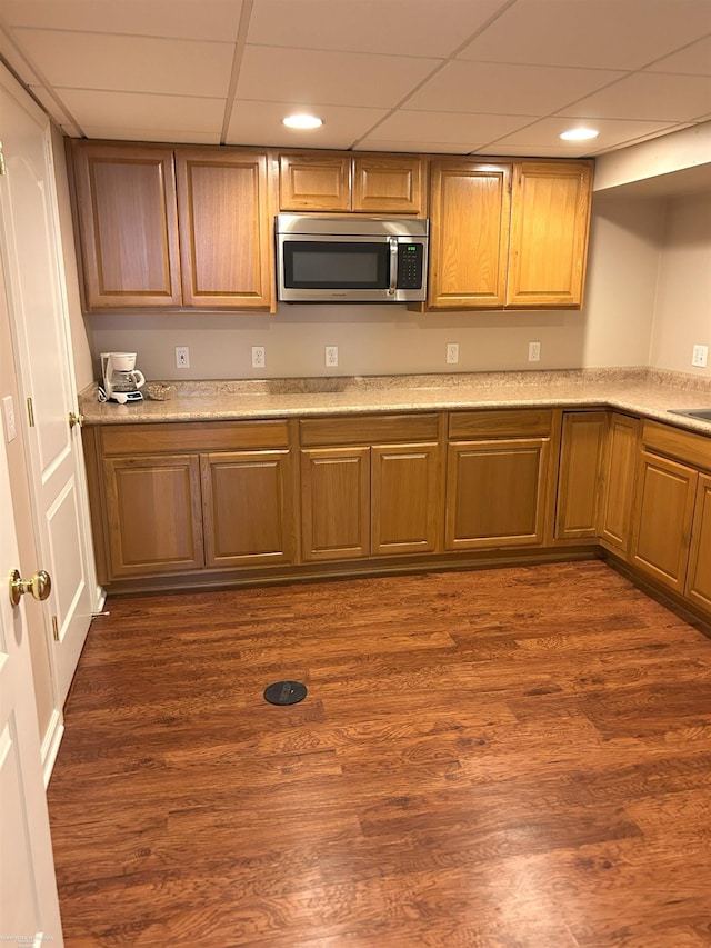 kitchen with recessed lighting, stainless steel microwave, a drop ceiling, and dark wood-style floors