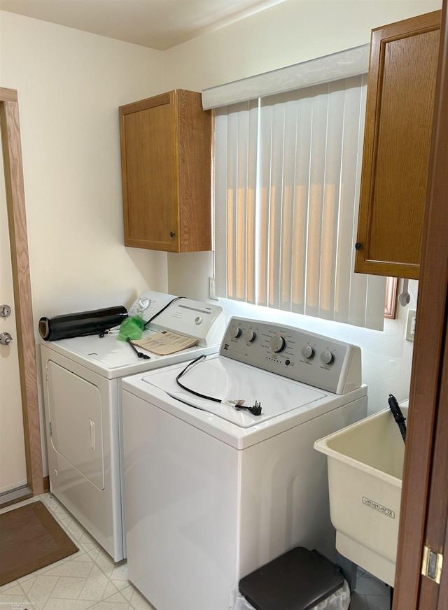 clothes washing area with independent washer and dryer, a sink, and cabinet space