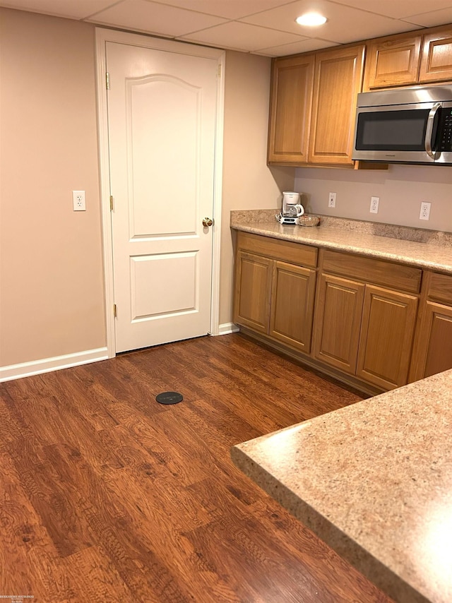 kitchen featuring light countertops, dark wood-style flooring, stainless steel microwave, and baseboards