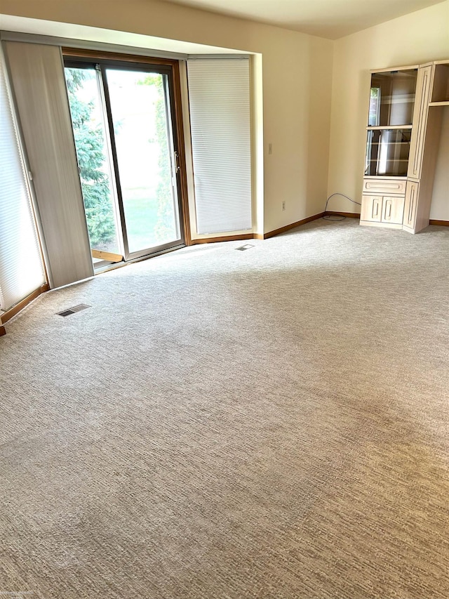 spare room featuring carpet floors, baseboards, and visible vents