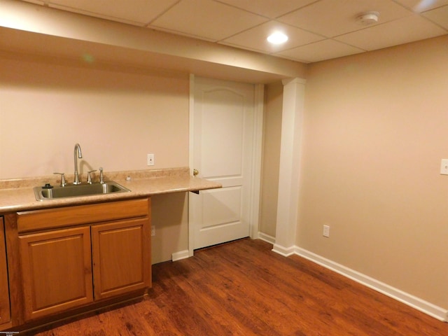 bar with dark wood-style flooring, a sink, baseboards, a drop ceiling, and recessed lighting