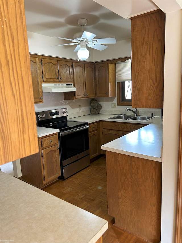 kitchen featuring under cabinet range hood, light countertops, a sink, and stainless steel range with electric stovetop