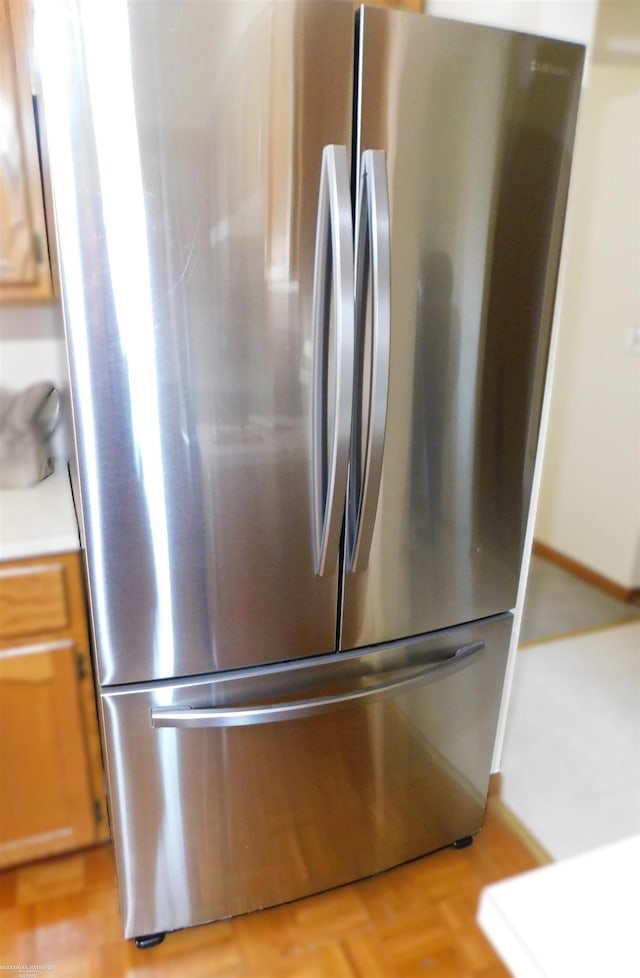 room details with freestanding refrigerator, brown cabinets, and light countertops