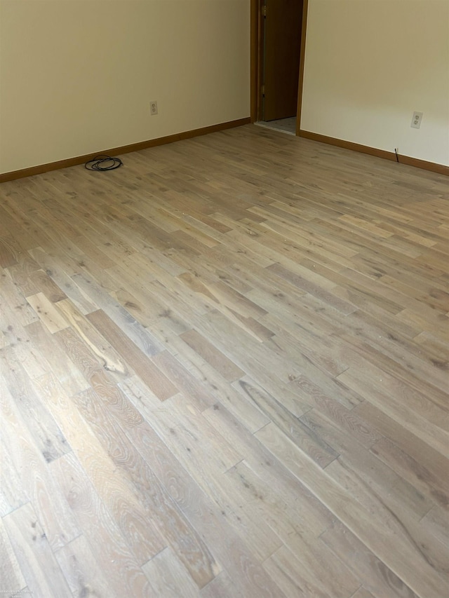unfurnished room featuring baseboards and light wood finished floors