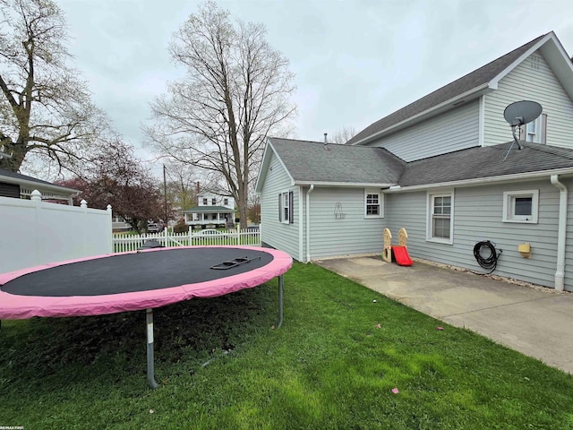 303 N 5th St, Saint Clair, MI 48079 - back of property with a trampoline, fence, a shingled roof, and a yard