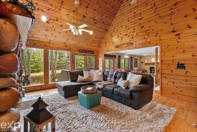 living room with wood-type flooring, wooden walls, high vaulted ceiling, and ceiling fan