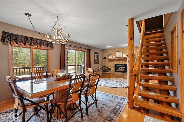 dining room with a fireplace, stairway, a chandelier, and light wood-type flooring