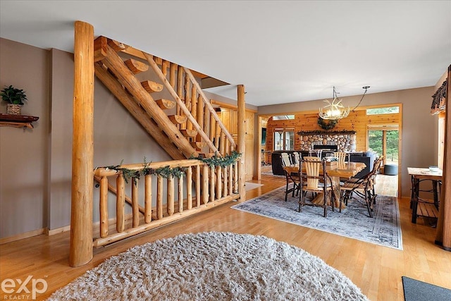 dining area with a stone fireplace, stairway, and wood finished floors