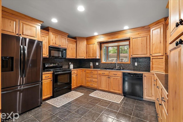 kitchen featuring dark countertops, black appliances, backsplash, and a sink
