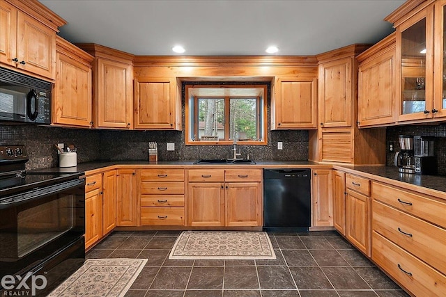 kitchen featuring tasteful backsplash, glass insert cabinets, a sink, dark countertops, and black appliances