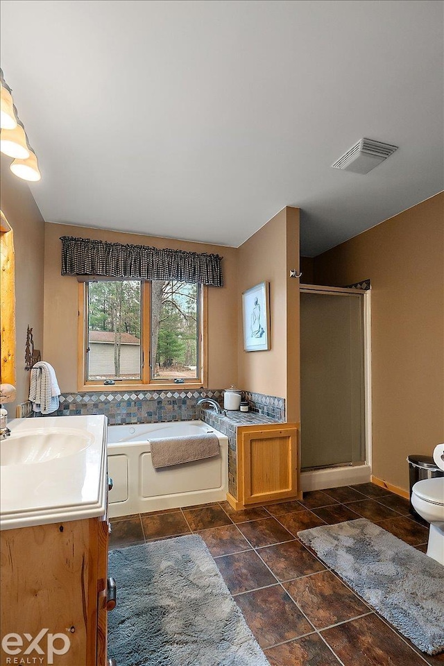 bathroom featuring toilet, vanity, visible vents, a stall shower, and a garden tub