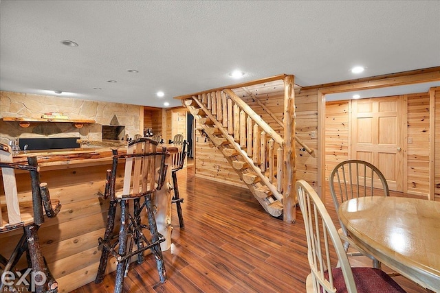 dining room with wooden walls, recessed lighting, stairway, and wood finished floors