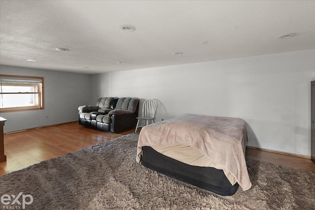 bedroom featuring recessed lighting, a textured ceiling, wood finished floors, and baseboards