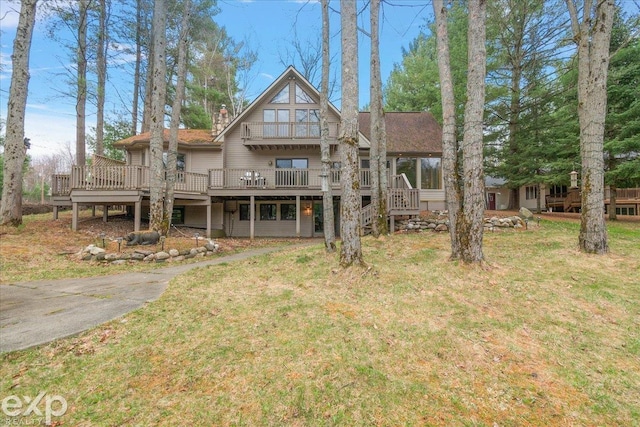 rear view of house with a deck, a yard, and a chimney