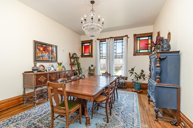 dining room with a chandelier, baseboards, and wood finished floors