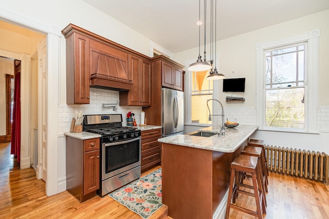 kitchen featuring radiator heating unit, stainless steel appliances, light wood-type flooring, and a sink