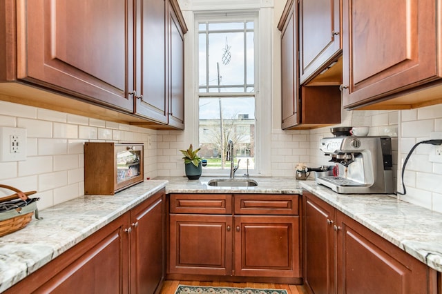 kitchen featuring light stone counters, backsplash, plenty of natural light, and a sink