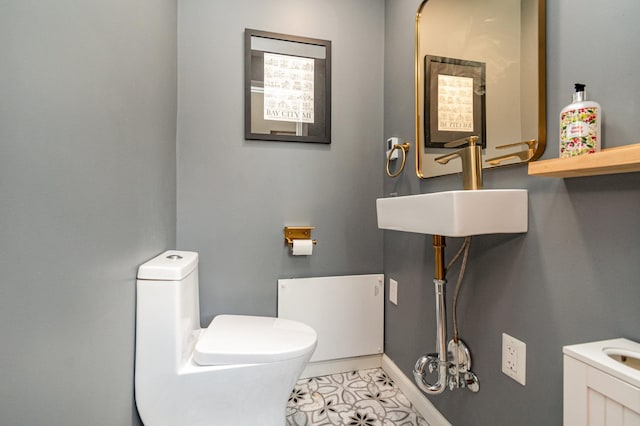 bathroom with baseboards, toilet, and a sink