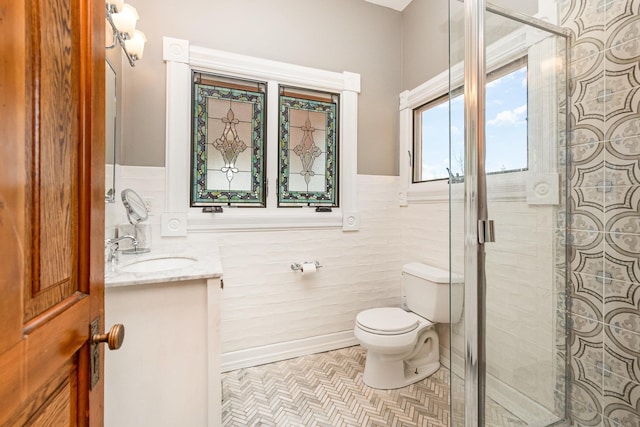 bathroom with toilet, vanity, a shower stall, and tile walls