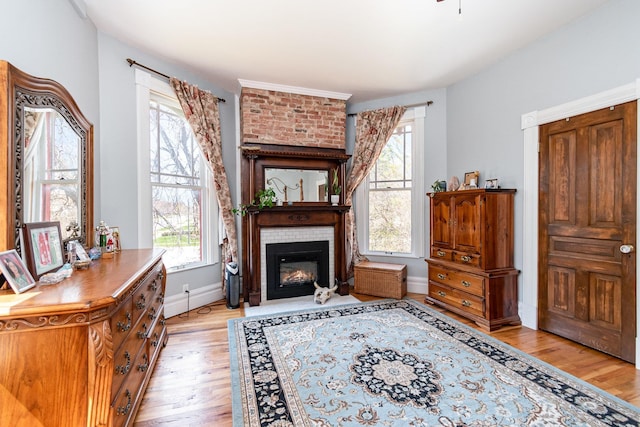 living area featuring baseboards, light wood-type flooring, and a brick fireplace