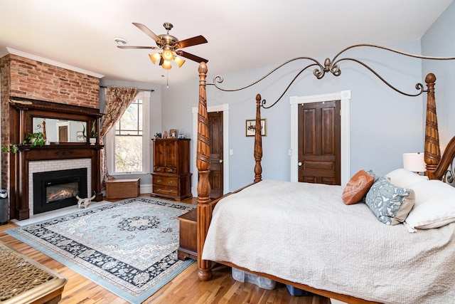 bedroom with wood finished floors, a ceiling fan, and a fireplace
