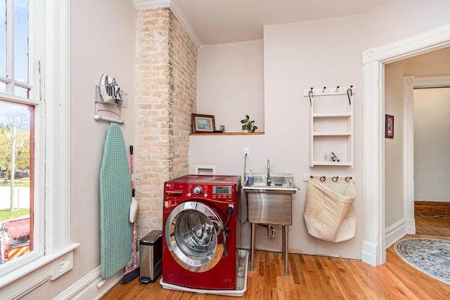 laundry room with wood finished floors, laundry area, washer / dryer, a sink, and baseboards