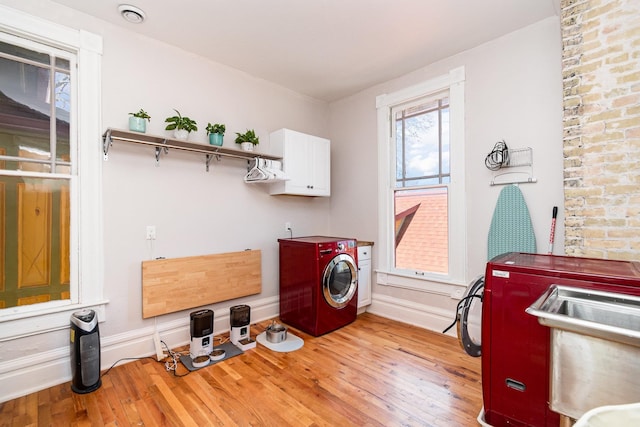 washroom with light wood finished floors, cabinet space, and washer and clothes dryer