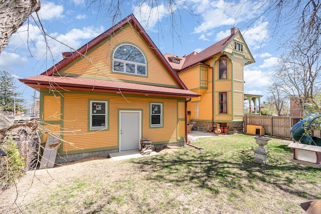 back of property with a lawn, entry steps, and fence