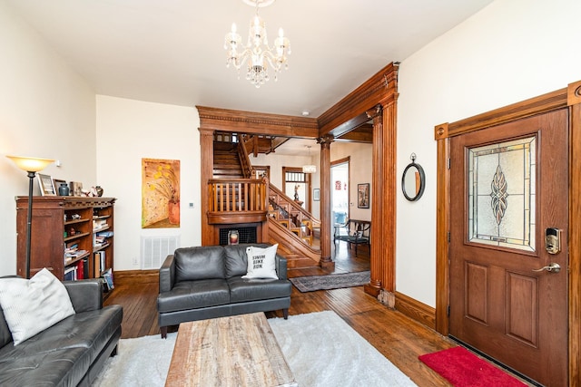 living area featuring baseboards, visible vents, a notable chandelier, and stairs