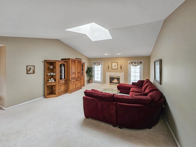 carpeted living area featuring a glass covered fireplace, vaulted ceiling with skylight, and baseboards