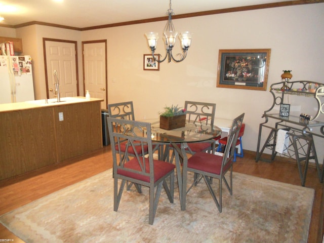 dining space with ornamental molding, light wood-style floors, and a notable chandelier