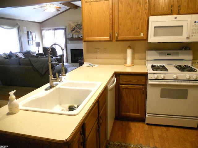 kitchen featuring wood finished floors, white appliances, light countertops, a sink, and open floor plan
