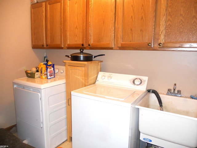 washroom featuring washing machine and clothes dryer, cabinet space, and a sink
