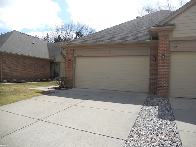 view of front of property with driveway, roof with shingles, brick siding, and a garage