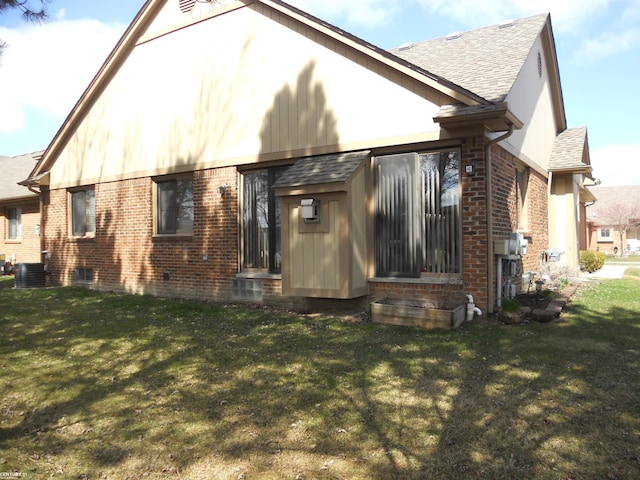 rear view of property with a lawn, central air condition unit, a shingled roof, and brick siding