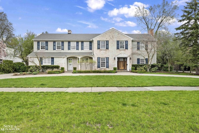 colonial home featuring a chimney and a front yard