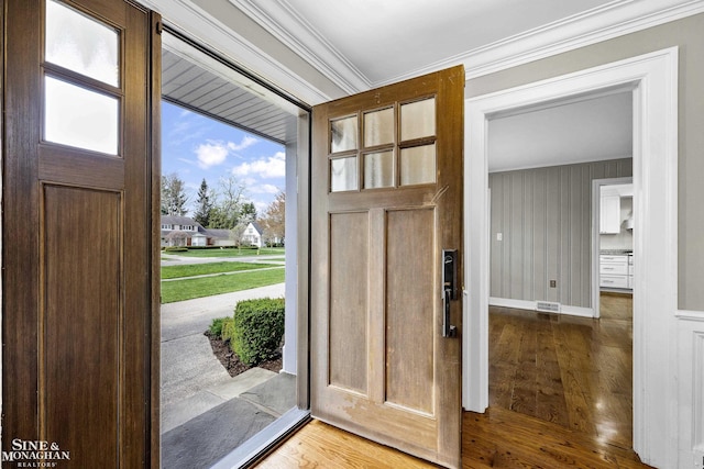foyer featuring visible vents, wood finished floors, ornamental molding, and baseboards