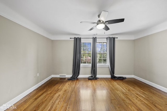 unfurnished room featuring visible vents, ceiling fan, wood finished floors, and baseboards