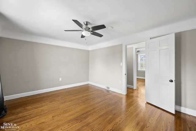 spare room featuring wood finished floors, ceiling fan, visible vents, and baseboards