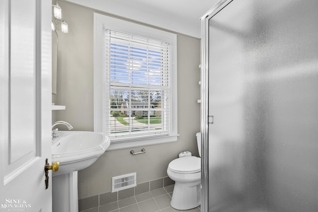 bathroom featuring tile patterned floors, a shower stall, toilet, baseboards, and visible vents