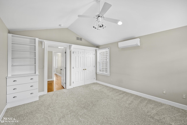 unfurnished bedroom featuring a wall mounted air conditioner, visible vents, vaulted ceiling, carpet, and baseboards
