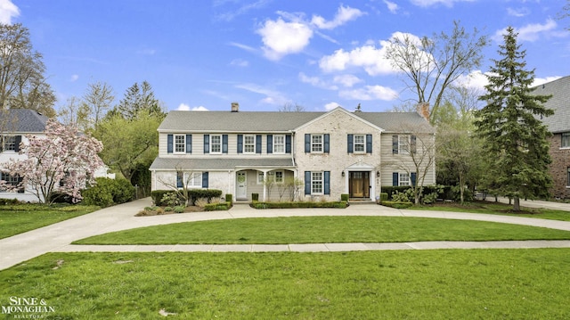 view of front of home featuring a chimney, a front yard, and curved driveway