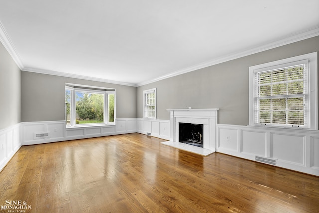 unfurnished living room featuring visible vents, a fireplace with raised hearth, a decorative wall, and ornamental molding