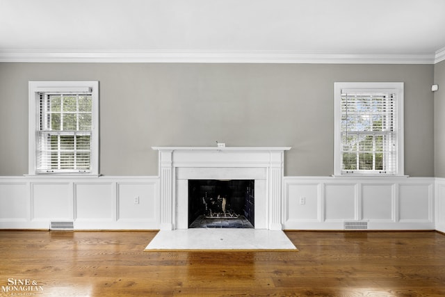 unfurnished living room featuring a fireplace with flush hearth, visible vents, and crown molding