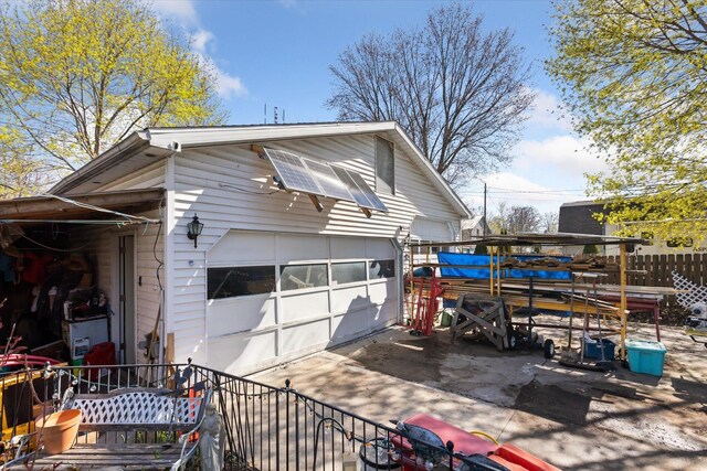 view of property exterior featuring a detached garage, fence, and an outdoor structure