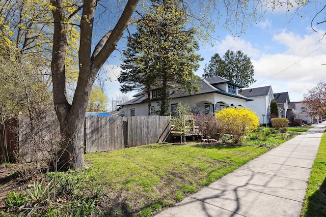 view of side of home featuring fence and a yard