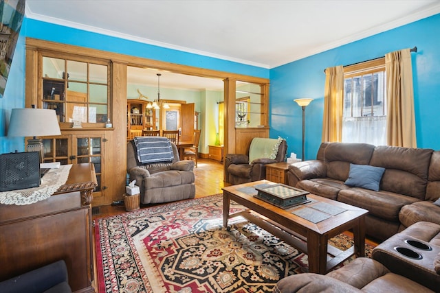 living area with ornate columns, wood finished floors, an inviting chandelier, and crown molding