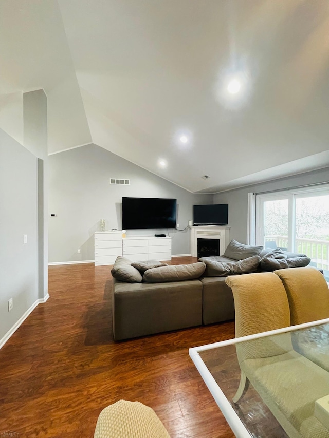 living area with visible vents, baseboards, vaulted ceiling, a fireplace, and wood finished floors