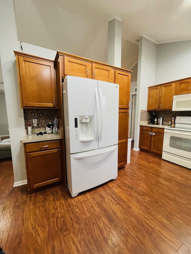 kitchen with light countertops, white appliances, dark wood-style flooring, and backsplash